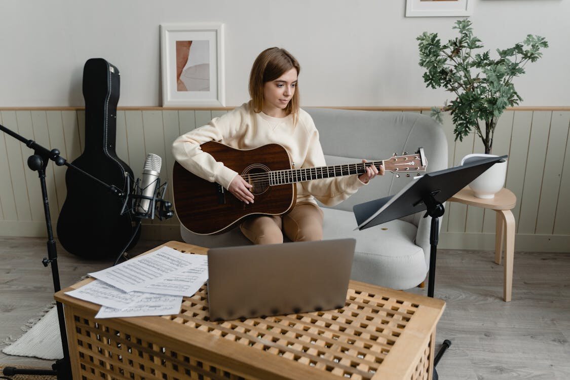 A woman playing guitar while using the best music composition software