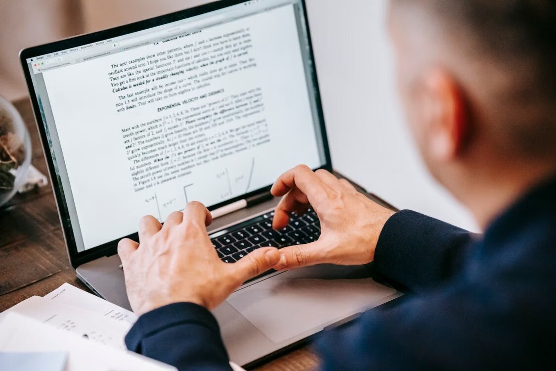 Person reviewing a digital document on a laptop at a desk.