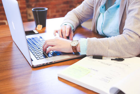 A person using a MacBook on a table. 