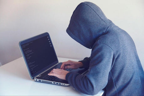 An anonymous person writing code on a laptop