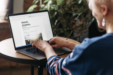 Woman creating a travel journal in Microsoft Word on a laptop.