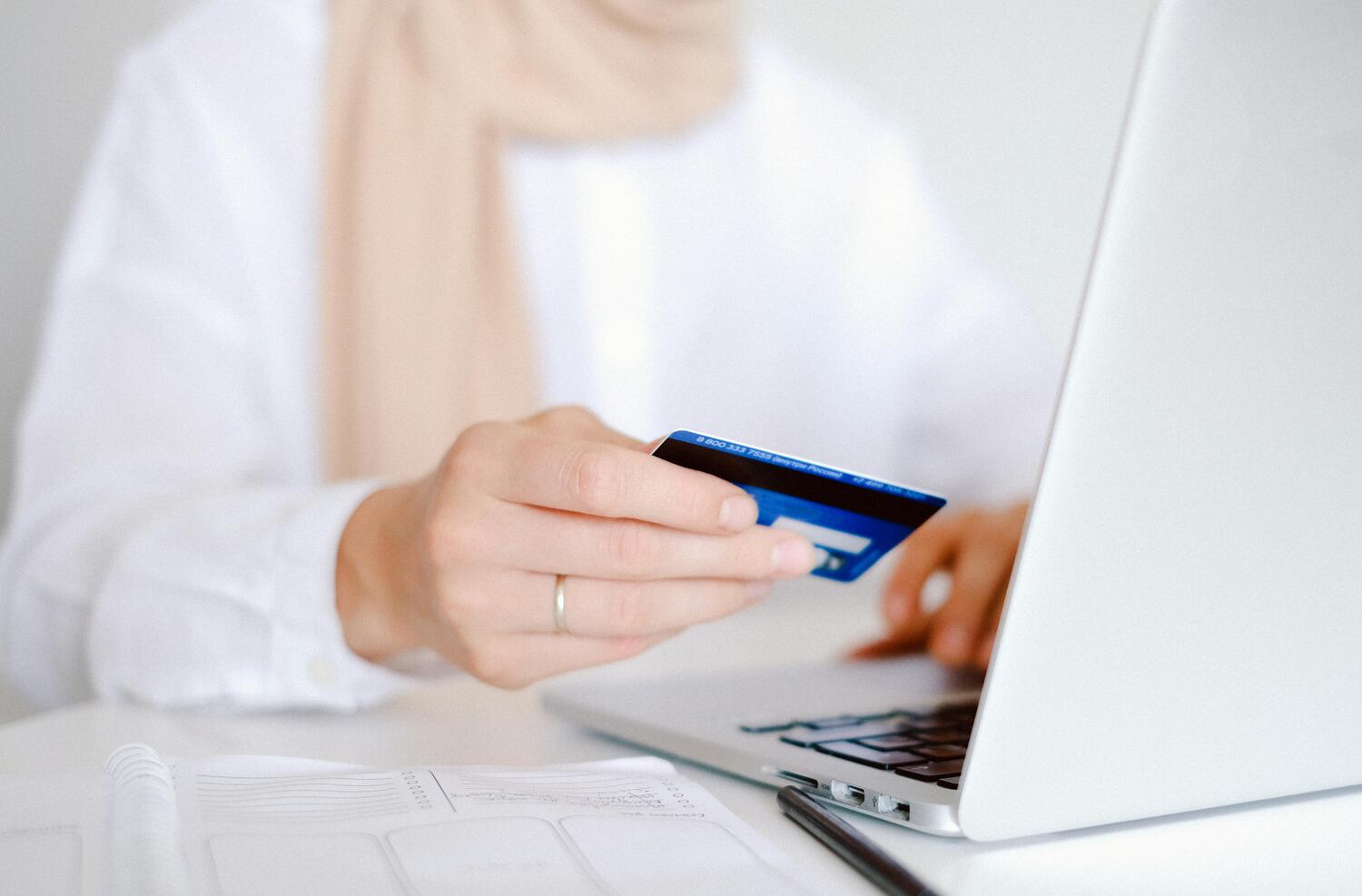 woman holding credit card while doing holiday shopping online