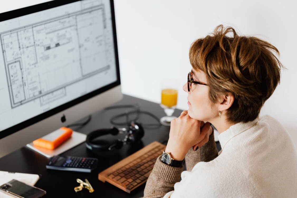Woman looking at an architectural CAD drawing on a desktop computer